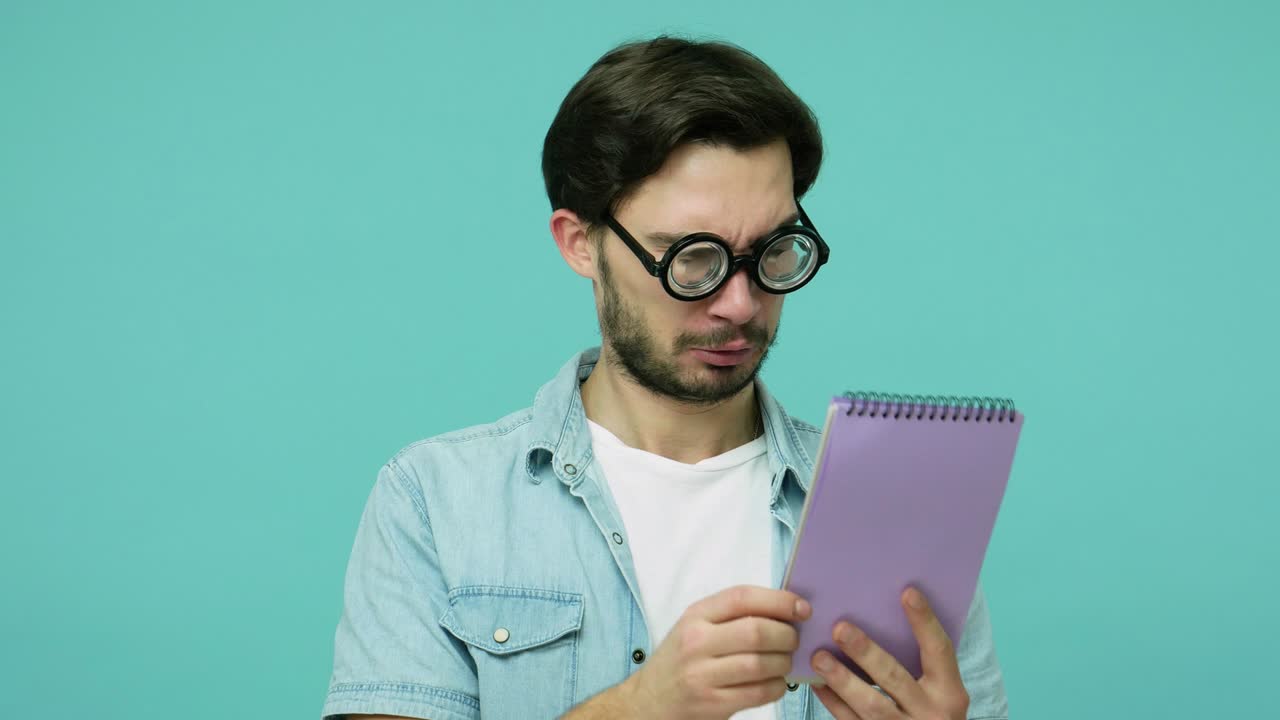 un geek raro y cómico con gafas estudiando. un tipo barbudo inteligente con gafas dioptricas redondas leyendo entradas de cuadernos.