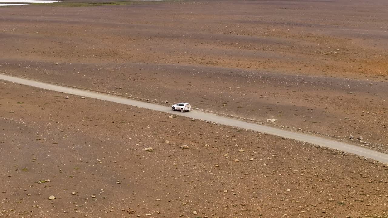 Aerial tracking shot of white 4x4 car on Sandy road of Iceland landscape. Sunny summer day in Kjalvegur. Following shot