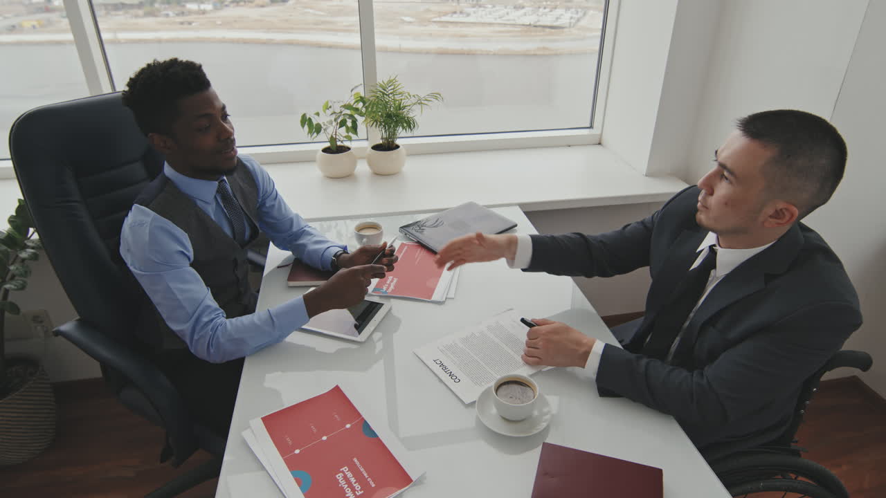 Businessman Signing Contract and Shaking Hands with Colleague
