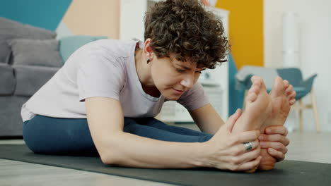 woman practicing seated forward bend yoga pose at home