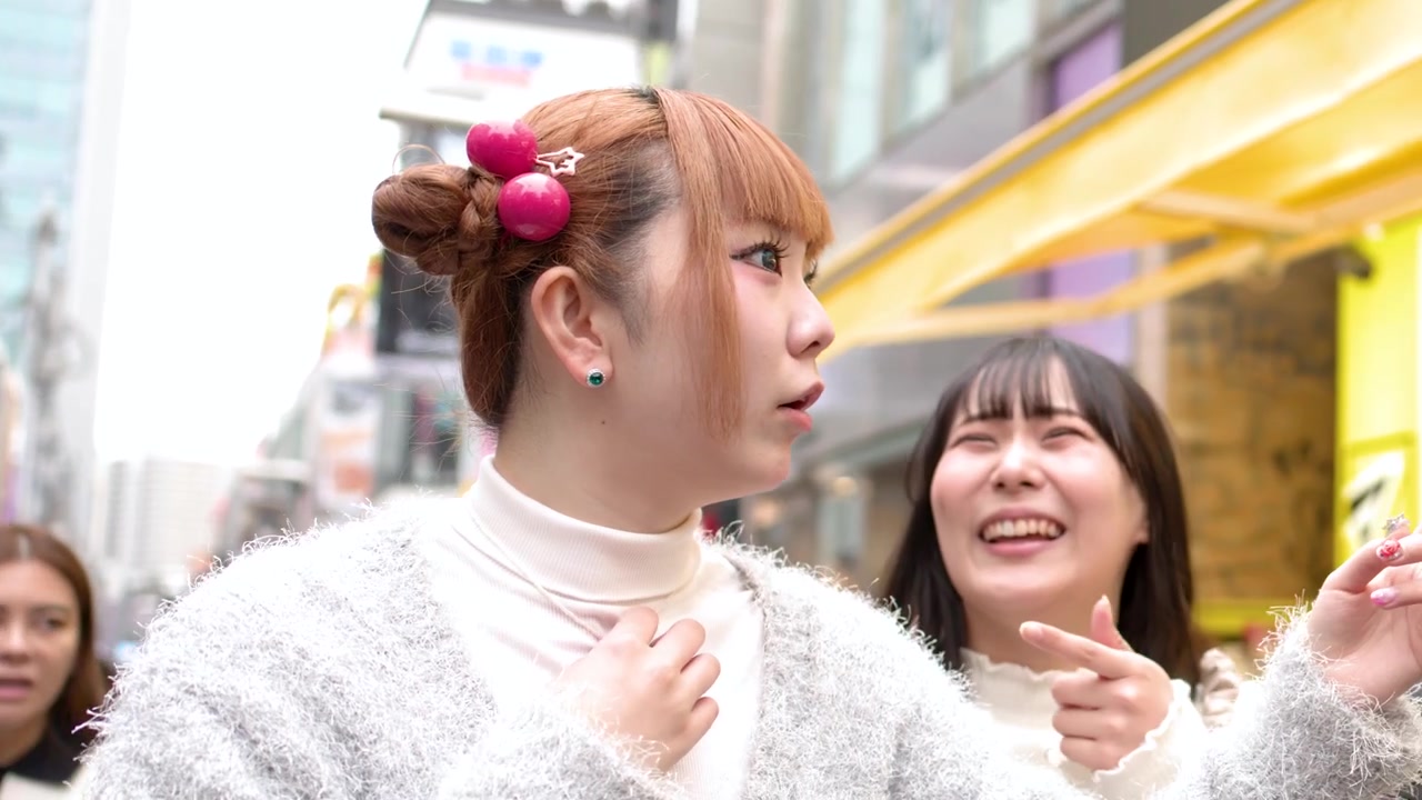 原宿の賑やかな竹下通りを散策しながら、話し、微笑む2人の若い日本人女性。