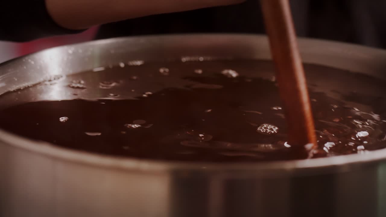 close up shot of boiling syrup in a big pot stirring with wooden spoon