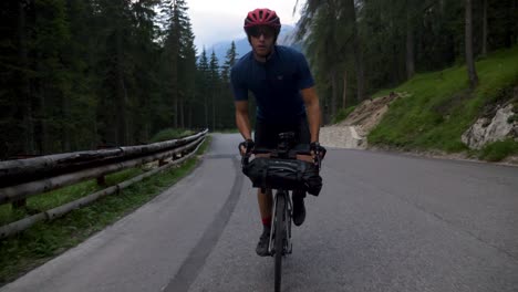 healthy male cycling behind a car at high speed in the mountains in the italian dolomites in italy, europe
