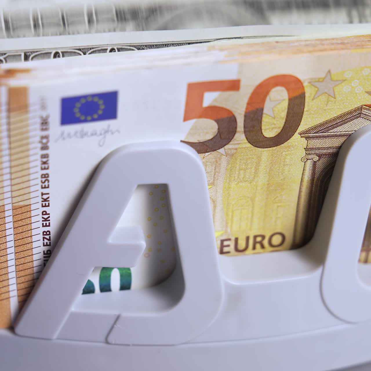 Paper money in counting machine. Many banknotes of fifty euro and dollar bills in the counting equipment. Financial transactions in bank. Close-up