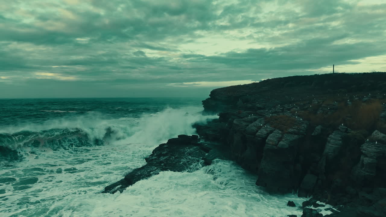 Aerial View of Powerful Ocean Waves Crashing Against a Rocky Cliff