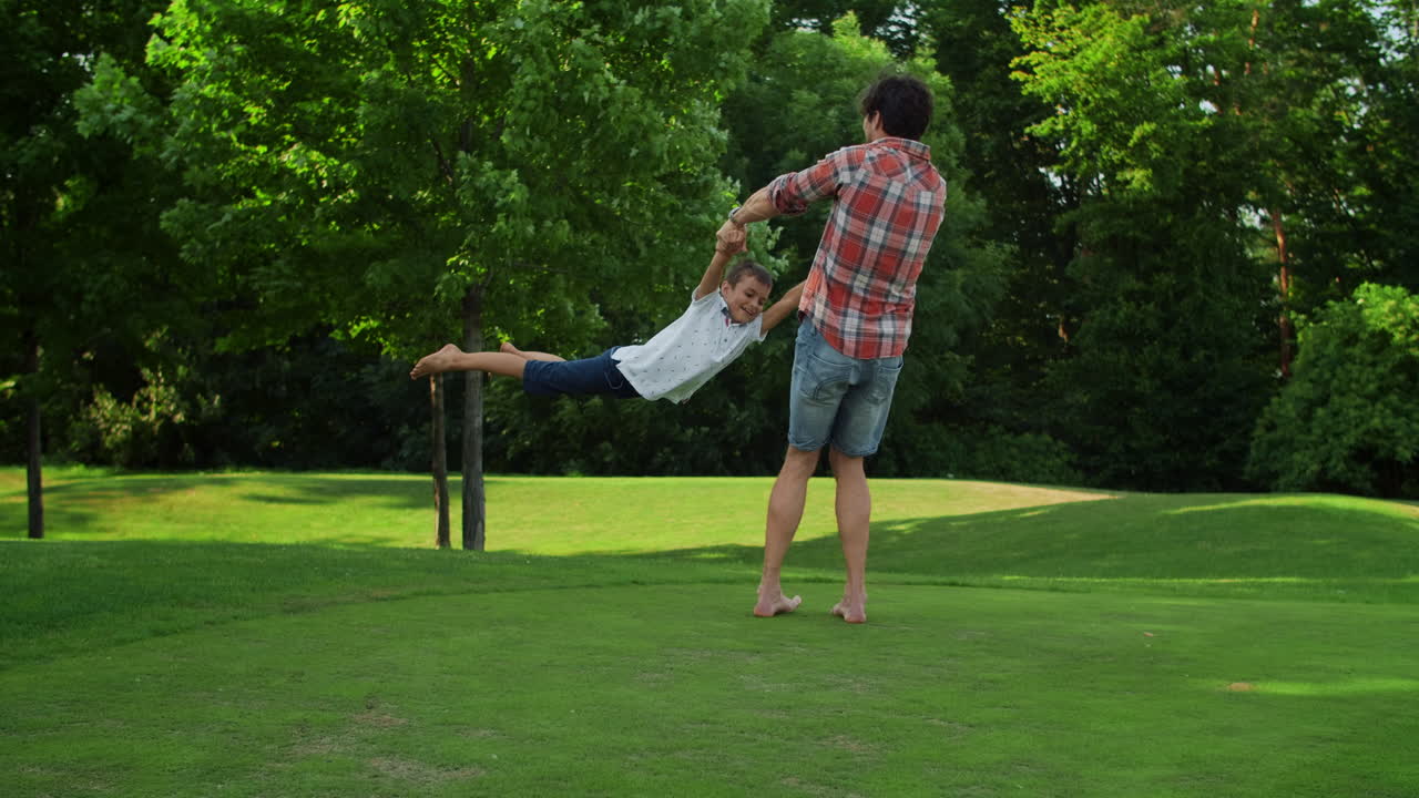 미소 짓는 남자 녹색 초원에서 회전하는 소년