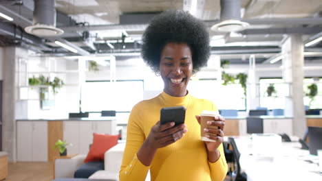 Feliz-Mujer-De-Negocios-Afroamericana-Casual-Caminando-Y-Usando-Un-Teléfono-Inteligente-En-La-Oficina,-Cámara-Lenta