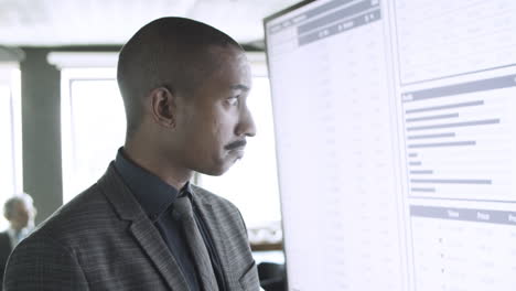 pensive mixed-raced businessman checking data in tablet