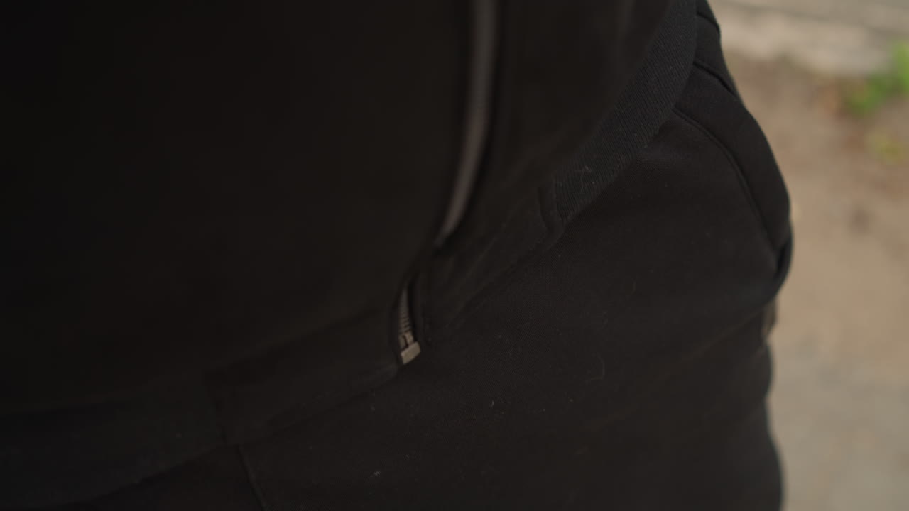 パーカーを調整する男性、都会のストリートウェアを着た男性、都市部でパーカーを調整する男性のクローズアップ写真、都会でランニングに出かける前にジャケットを締める男性のクローズアップ