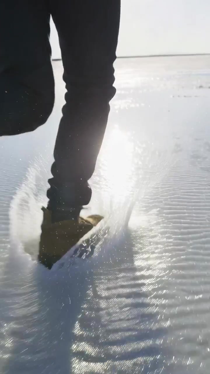 Vertikal video: Støvle rammer overflade og laver ringe, mens mand går mod solen, brune støvler, mørke bukser.
