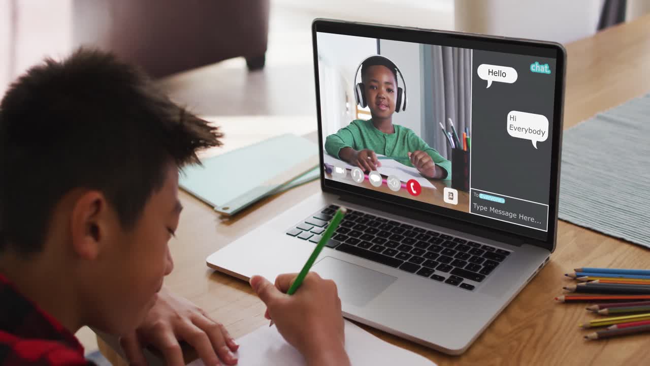 chico asiático haciendo la tarea y teniendo una videollamada con un compañero de clase en una computadora portátil en casa