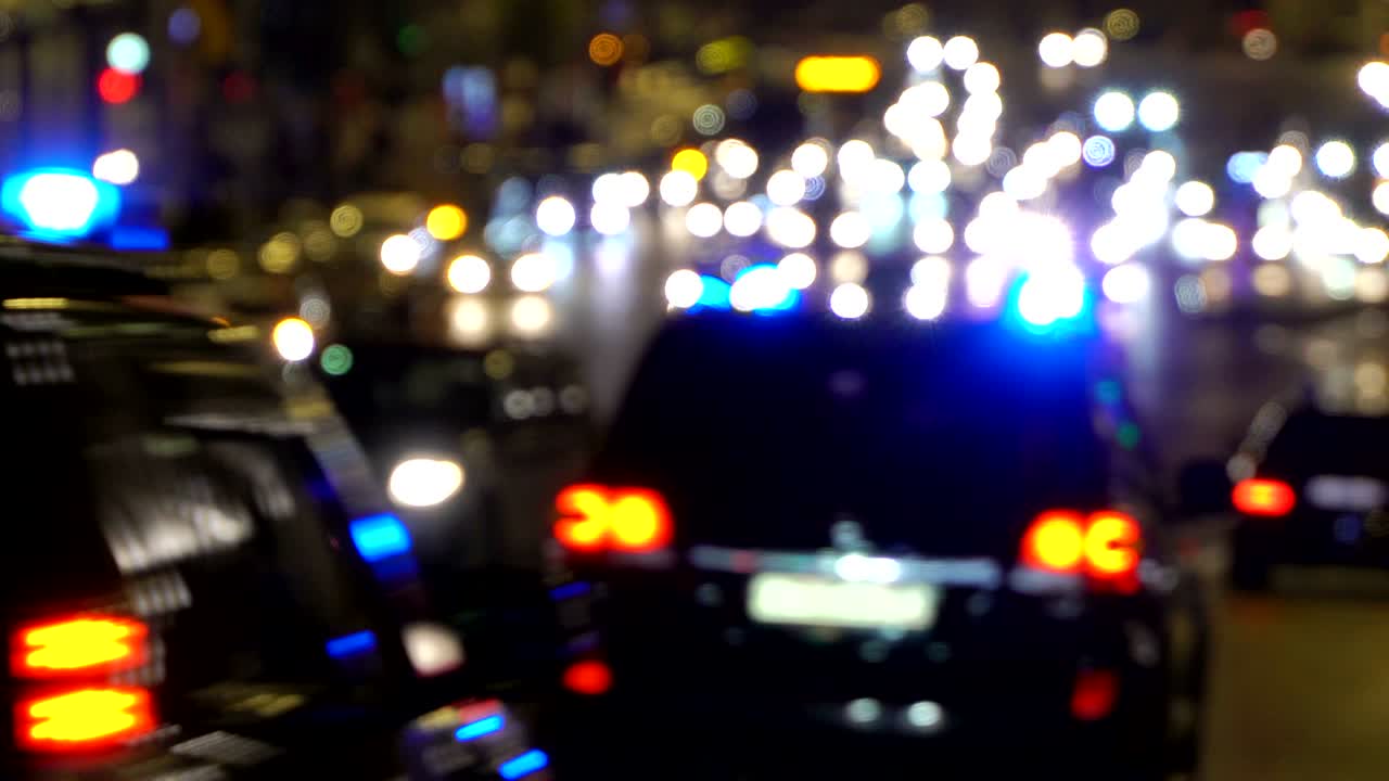 luces de automóviles de manejo nocturno de la ciudad. atasco de tráfico. luces de emergencia del coche de policía por la noche fuera de enfoque. reflectores de automóviles en la carretera mojada después de la lluvia borrosa