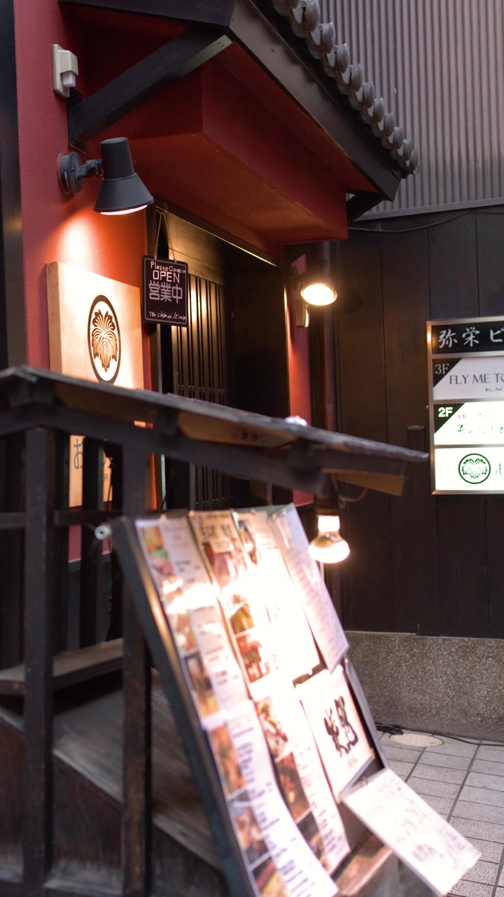 Stillbilde av en opplyst restaurantinngang og menytavle om natten i Kyoto