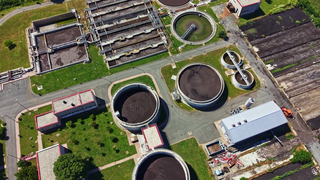Bird's eye view of a wastewater treatment plant with various tanks and structures showing the process of water purification