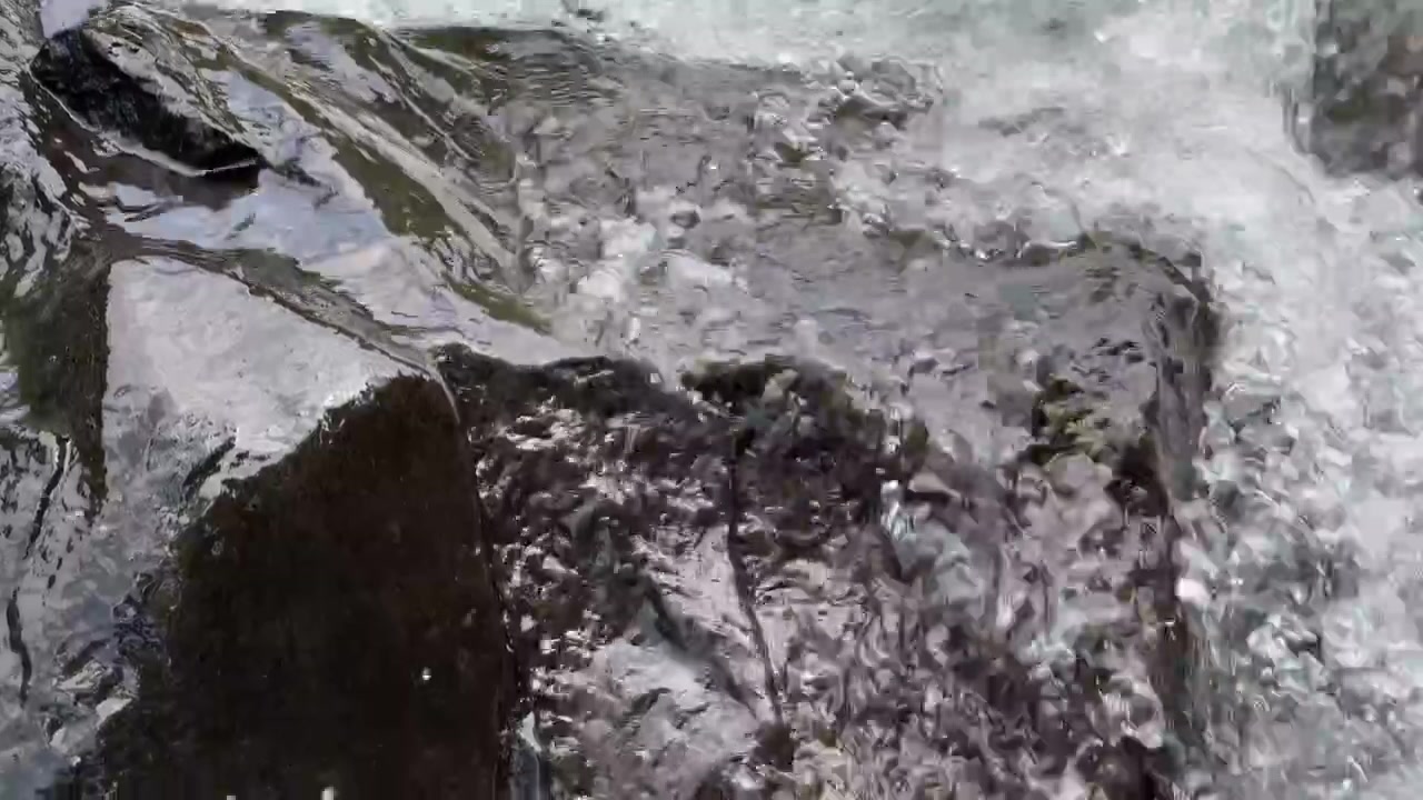 Acqua cristallina che scorre su rocce scure in un ruscello