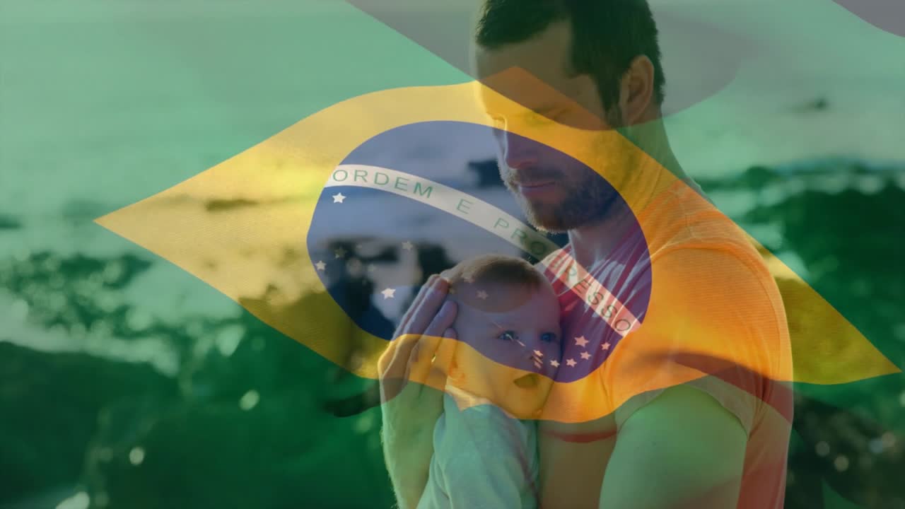Bebê arrulhando, pai segurando e acalmando a família em uma praia rochosa, com uma sobreposição da bandeira do Brasil em movimento.