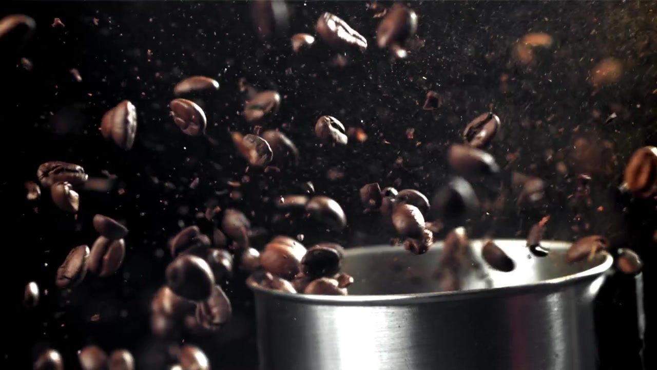Chicchi di caffè freschi tostati che cadono in un macinacaffè al rallentatore