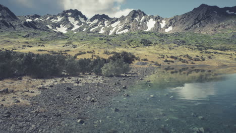 vista serena de la orilla del lago con montañas y bosque bajo un cielo despejado