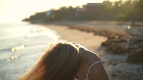 closeup slow motion of backlit mature woman throwing her hair from side to side on a beach