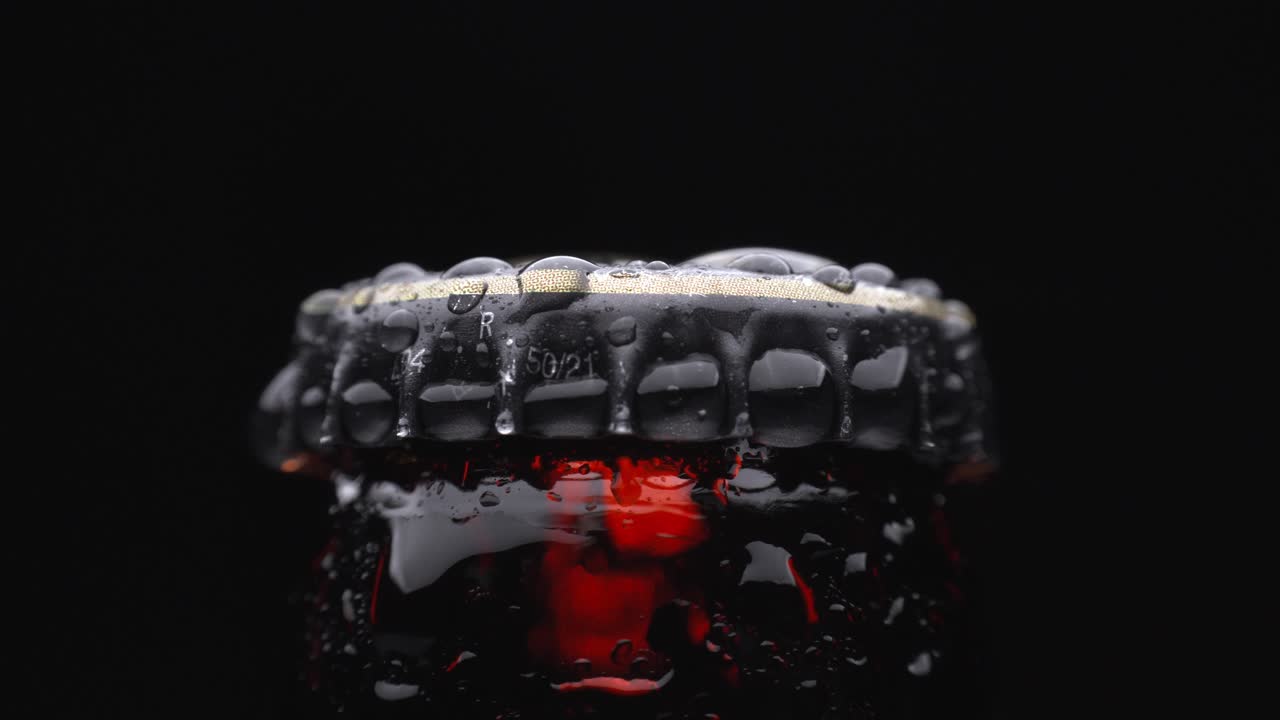 Foto de perto de uma tampa de garrafa de cerveja gelada girando com gotas de condensação na superfície