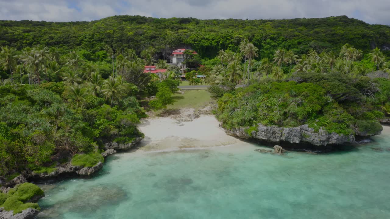 un dron captura una toma que vuela hacia la costa de una isla tropical, mostrando la exuberante vegetación verde, las aguas cristalinas y las playas de arena