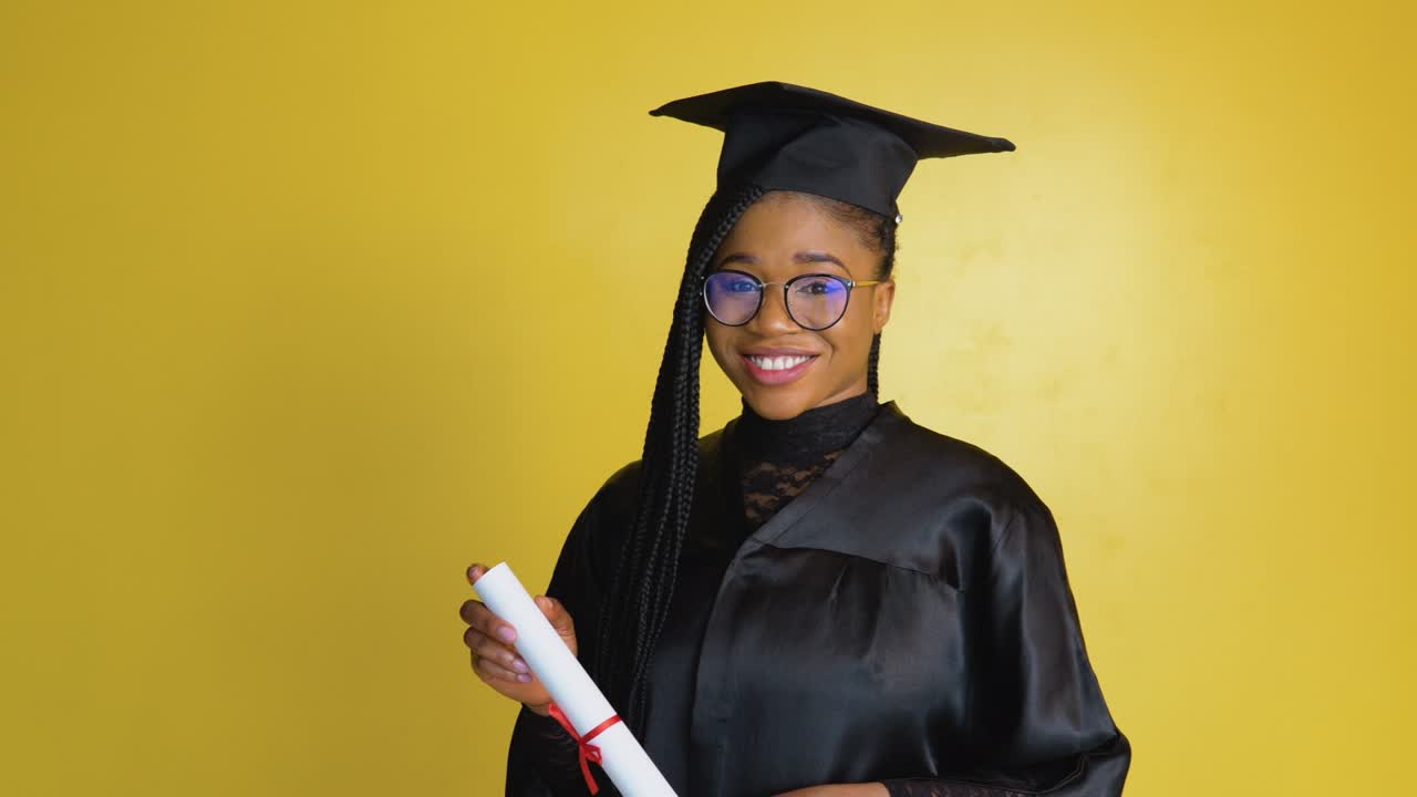 una mujer afroamericana tiene una maestría después de graduarse de la universidad. una estudiante feliz con un diploma sobre un fondo amarillo