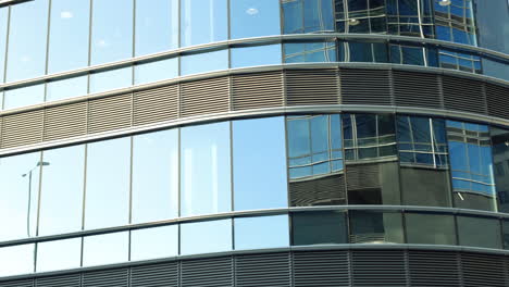 modern walls are made of glass and steel with reflections of buildings and blue sky