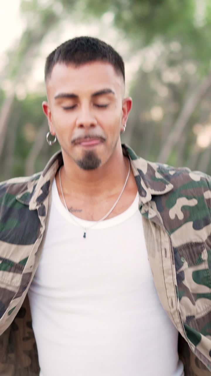Man in camouflage jacket singing and smiling outdoors