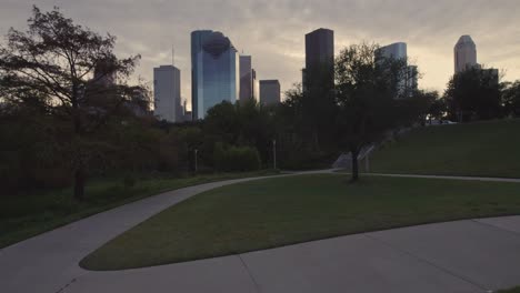 reveal of houston skyline from bayou park in the morning with clouds