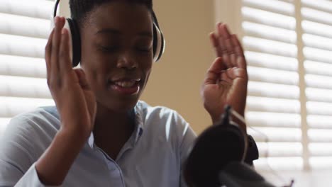 african american woman wearing headphones talking in microphone at home