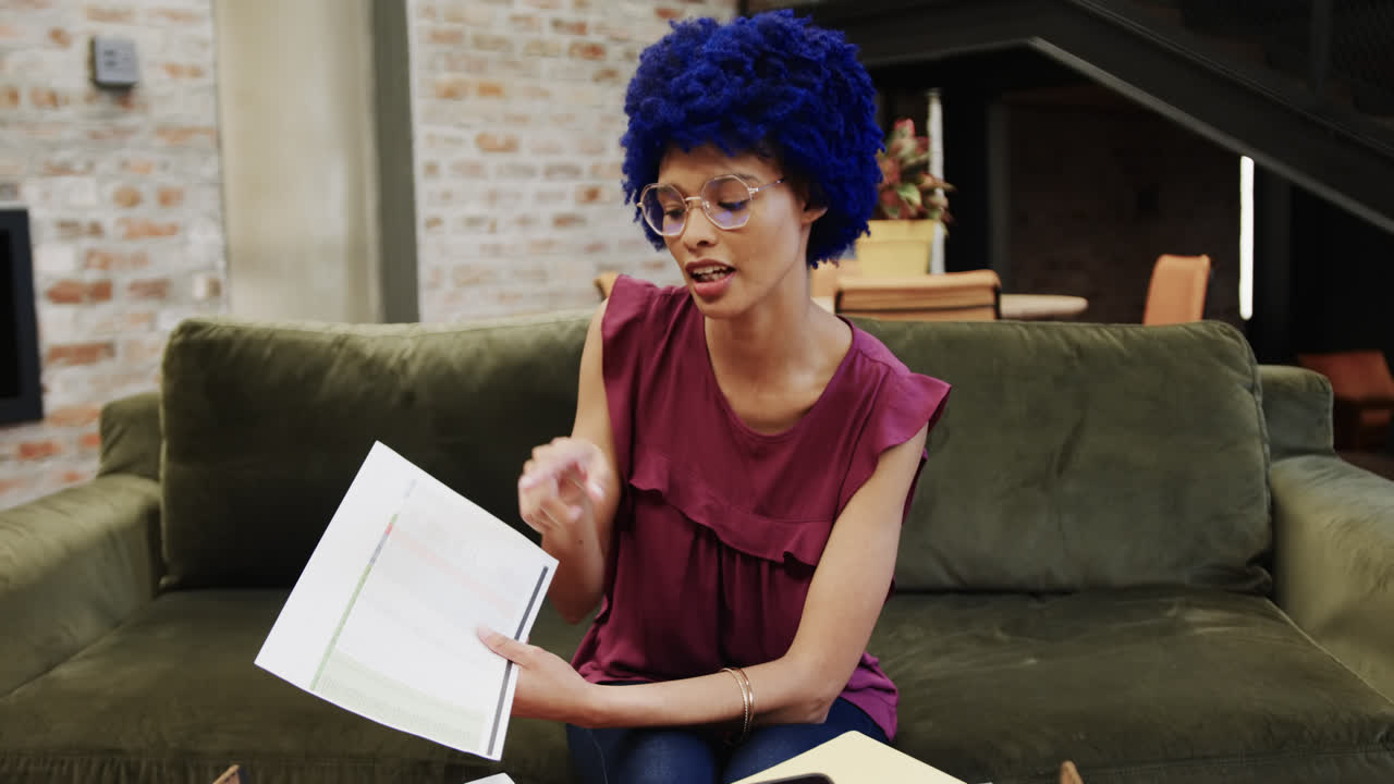 Forretningskvinde af blandet etnicitet med blåt afrohår har videoopkald på kontoret, slowmotion