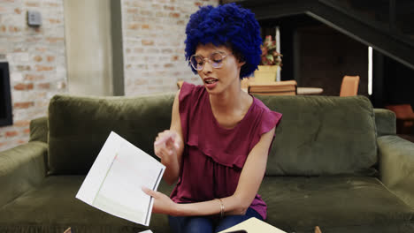 une femme d'affaires biraciale avec un afro bleu faisant un appel vidéo au bureau, au ralenti.