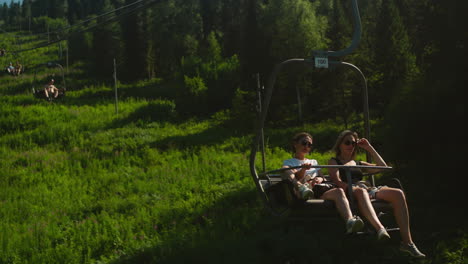 young women ride cable car down hilly mountain and enjoy view of dense forest. getting closer to nature and enjoying holiday at tourist destination