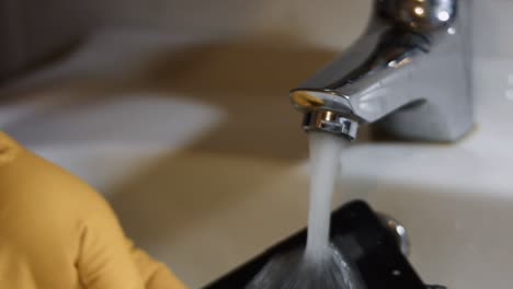 cellphone screen in hand under water in a washbasin. testing cellphone screen for water resistance. 4k video