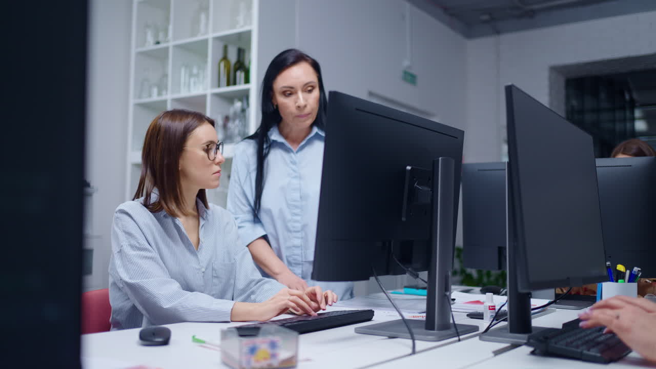 두 명의 여성이 사무실에서 책상에서 함께 일합니다.