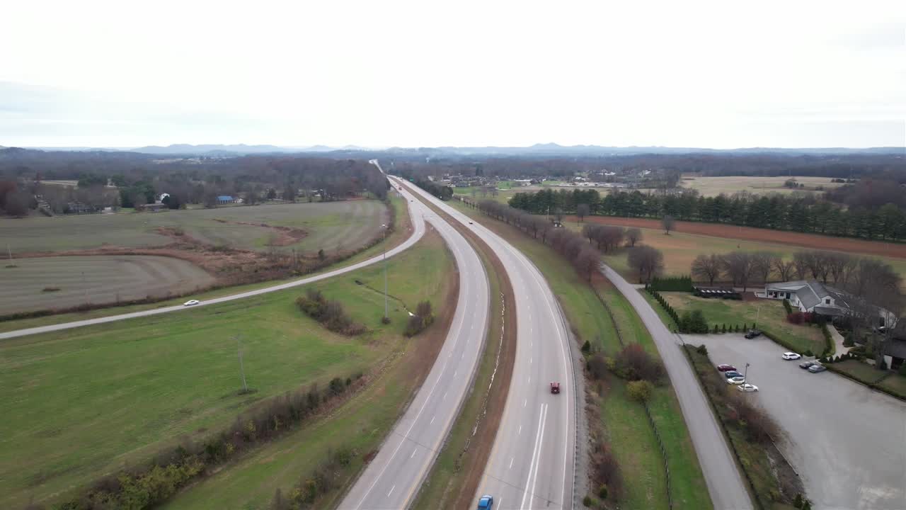 High-altitude drone shot of the Kentucky Bluegrass Parkway cutting through scenic rural landscape. Peaceful, wide view of transportation in motion