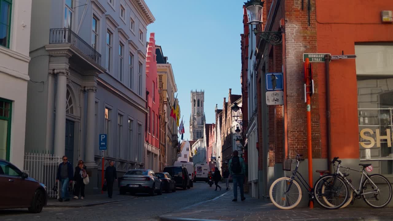 A quiet street in Bruges with colorful buildings, bicycles, and a van in the morning light
