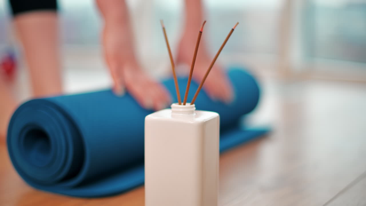 Gros plan sur une fille qui déroule un tapis de yoga bleu à l’intérieur. Préparation à la méditation