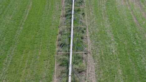 Vuelo-Con-Dron-Con-Vista-Cenital-En-Un-Campo-De-Cultivo-Visualizando-Una-Gran-Estructura-De-Riego-Por-Aspersión-Móvil-Apreciamos-Su-Formación-Metálica-Sus-Ruedas-No-Se-Mueven-Desde-Hace-Mucho-Tiempo