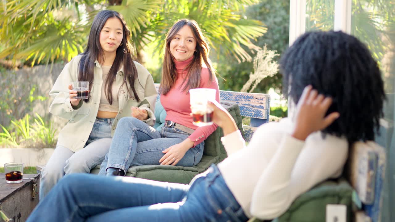 Multiethnic fiends chilling on the garden drinking wine during sunset