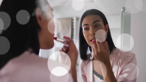 animation of light spots over biracial woman applying lipstick