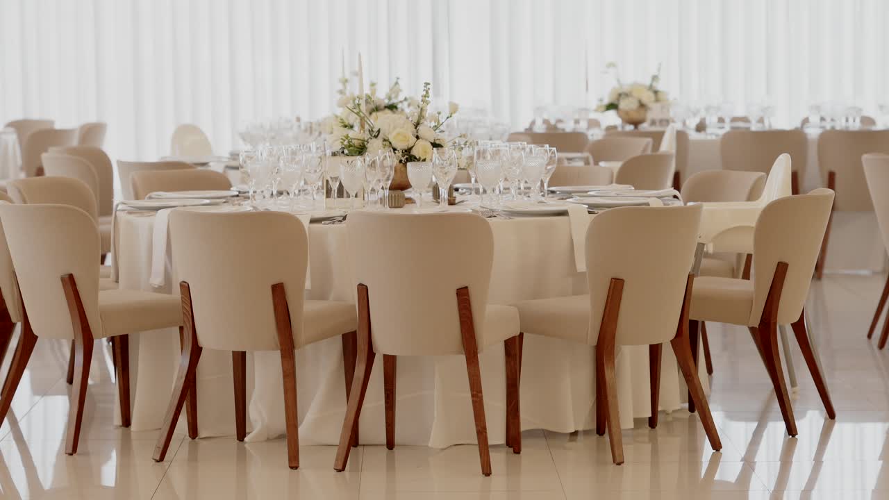 wide shot of wedding tables with white flowers and glassware in soft neutral decor
