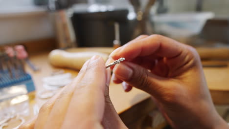 close up of female jeweller measuring handmade ring on gauge in studio