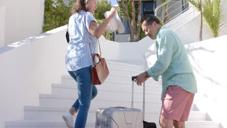 senior couple carrying luggage and climbing stairs, enjoying vacation together