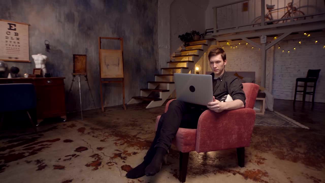 로프트 스타일의 가정 사무실에서 노트북으로 일하는 남자.