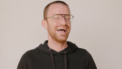 Red-haired-man-in-a-dirty-hoodie-awkwardly-laughing-in-a-terrible-way-on-a-white-backdrop