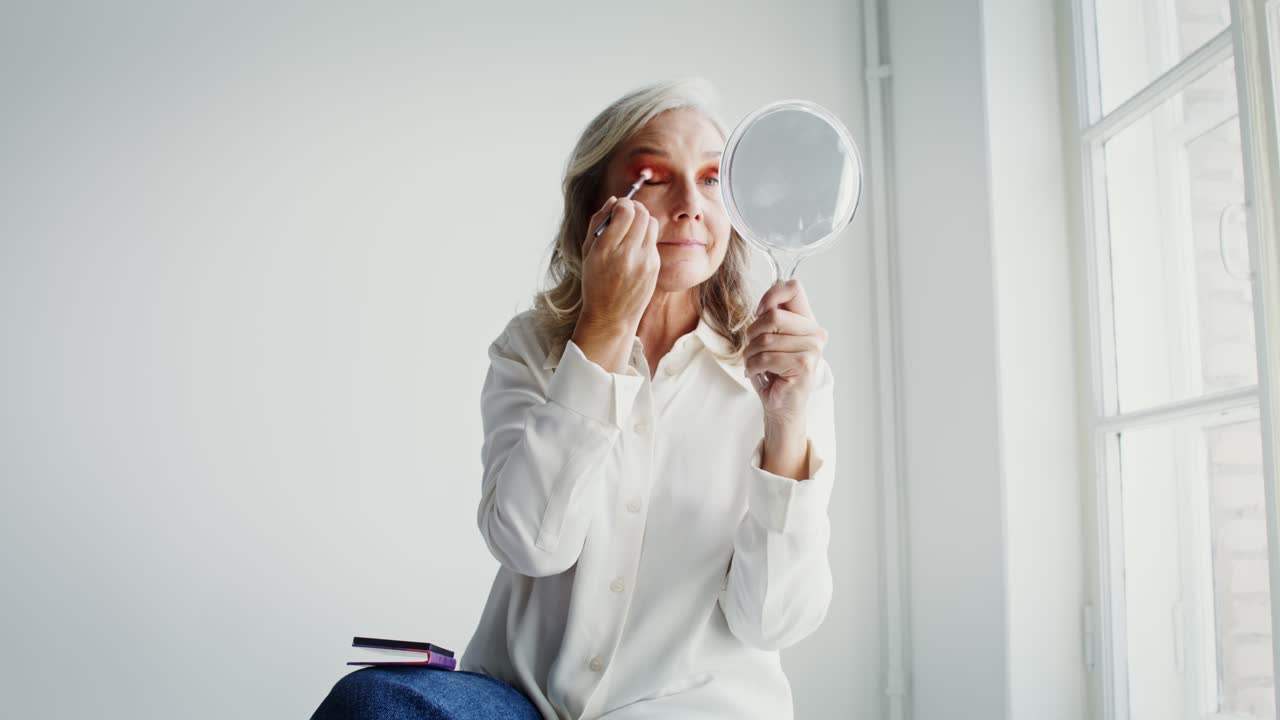 Woman Applying Makeup in Front of a Window