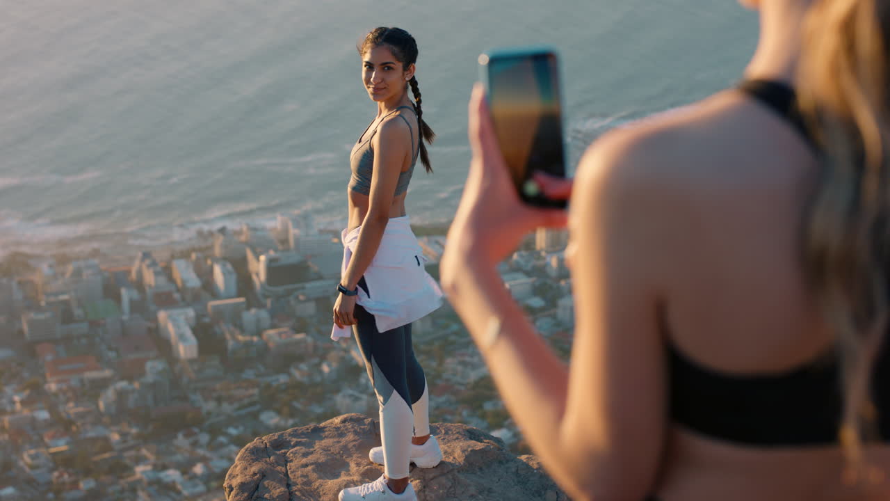 amigas tomando fotos en la cima de la montaña usando la cámara del teléfono inteligente mujer joven feliz posando para un amigo con el teléfono móvil compartiendo la aventura de senderismo en las redes sociales