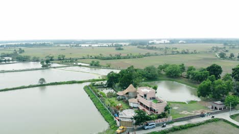 Toma-Aérea-De-Un-Pueblo-Con-Un-Resort-En-Bengala-Y-Lago-Y-Campo-En-Los-Alrededores