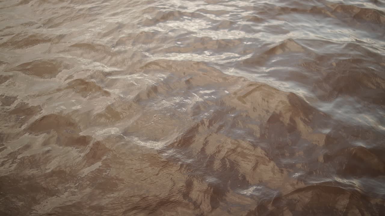 Close-up shot of dirty water flowing with visible ripples and movement in natural light
